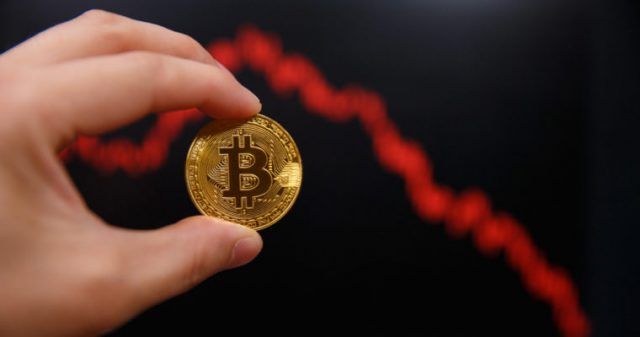 mão segurando uma moeda de bitcoin