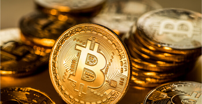 Bitcoins físicos brilhantes num fundo dourado