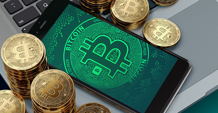 Smartphone com o símbolo BTC ao redor das pilhas de Bitcoin