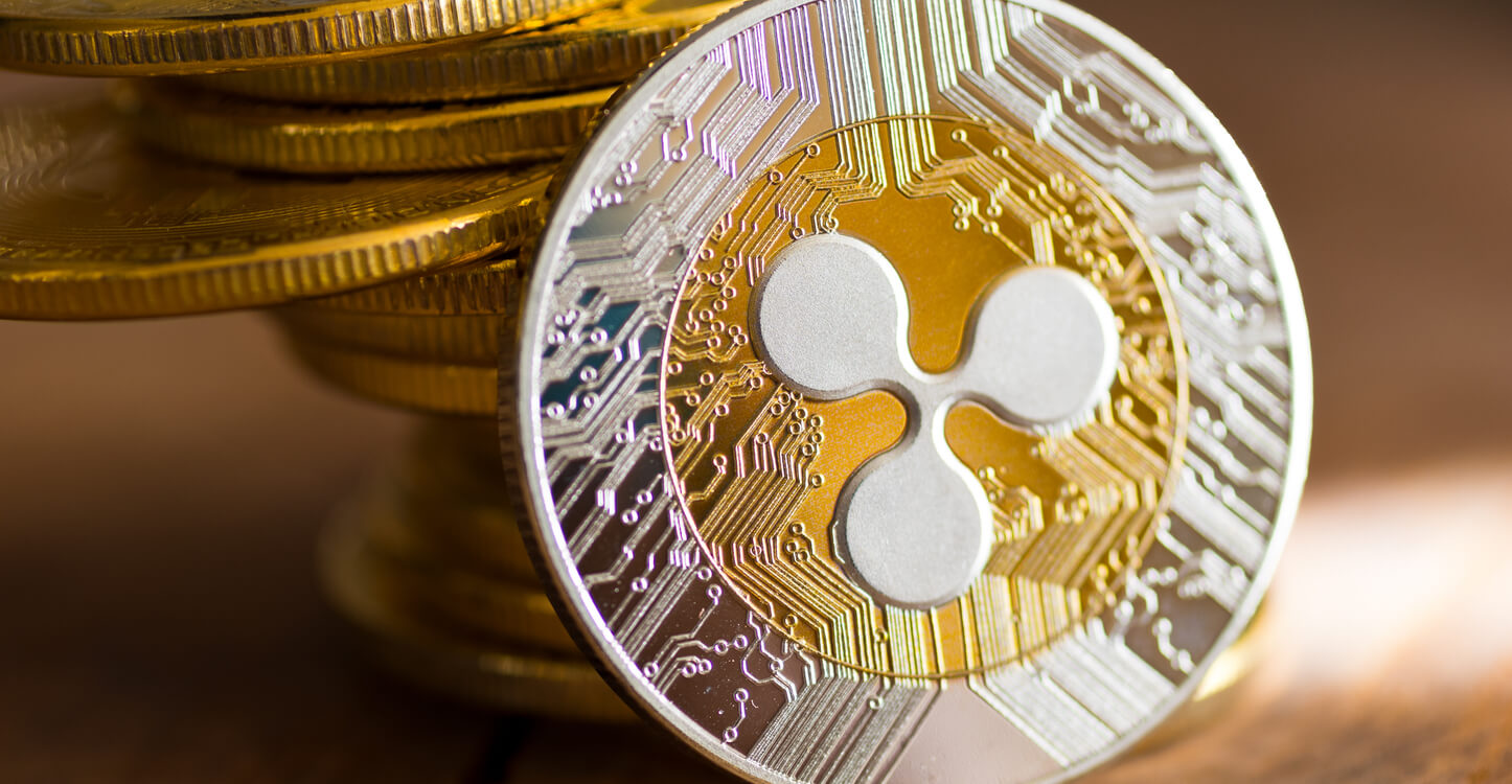 Pilha de moedas e XRP de ouro em fundo de madeira