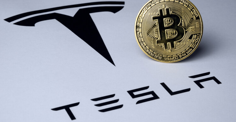 Uma imagem de um Bitcoin em superfície de papel mostrando o logotipo da Tesla