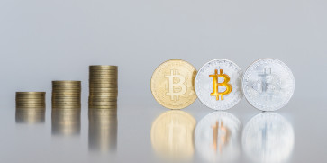 Três bitcoins ao lado de uma pilha de moedas